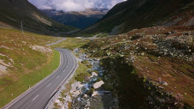 Winding road and creek in the Julier Pass, a high mountain pass in the Graub&uuml;nden canton, Switzerland. Aerial drone