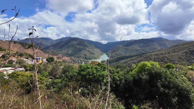 scenic wide shot of a vital water reservoir winding through the tropical mountains under a cloudy sky, South America