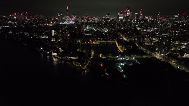 Aerial rotating shot in front of Shadwell Basin and London Skyline, night in UK