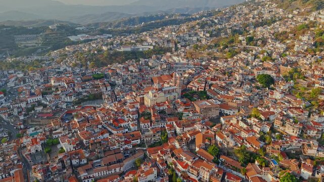 Aerial view of the town of Taxco on a sunny day, with colonial architecture featuring white houses and tiled roofs, and the Santa Prisca temple in the center, Guerrero, Mexico