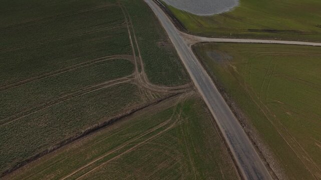 Backward Flight With Tilt‑Up Reveal Over Farmland Road With S-Shaped Curves