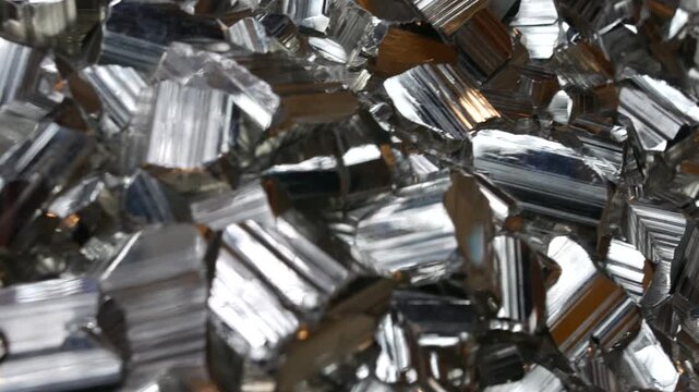 Pyrite crystals clustered in a mineral display, metallic cubic formations reflecting light while dense iron silver and gold tones creating a textured geological surface in a close-up macro view