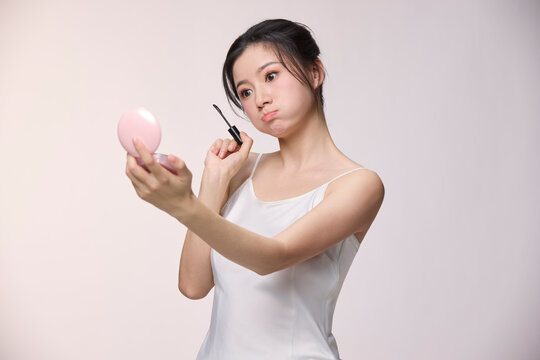 A beautiful young woman applies her mascara