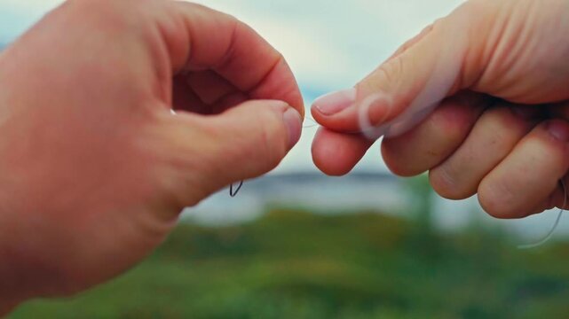 Hands Carefully Tie a Fishing Hook Onto a Thin Line Near the Coastal Waters of Sandland, Loppa Municipality, Finnmark, Norway - Close Up