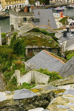 A view of the Meson de la Mar restaurant and surrounding buildings in a coastal town, with boats docked in the harbor.