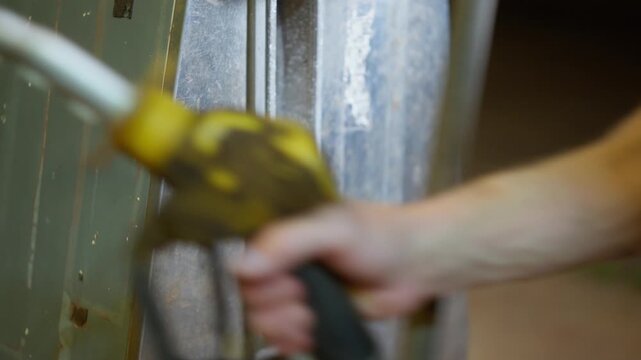 Close up of man retrieving a yellow fuel bowser handle to pump fuel late at night. Clip 8