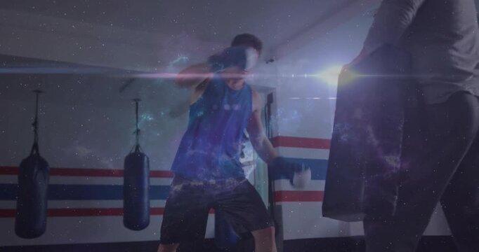 Trainer holding pads as boxer punching and kicking during boxing training, galaxy overlay building