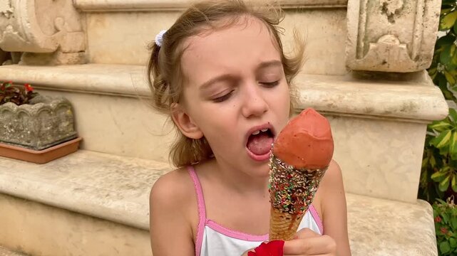  Young girl enjoying a fruit sorbet ice cream cone.