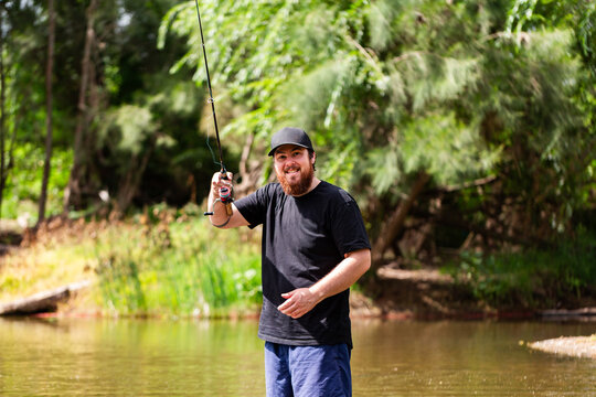 Happy person fly fishing in river standing in the water in summertime