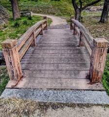Obraz premium traditional wooden bridge over a stream in a park with a path