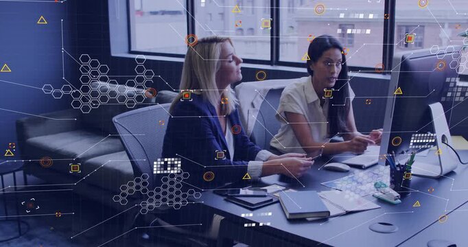 Two coworkers at desk, pointing at monitor and causing hexagon overlay confirming business decision