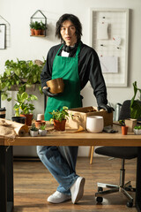 Young man cultivates joy among vibrant plants in a cozy floral workshop © Bliss