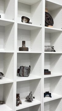 White cubby shelves holding car parts orderly rows of pistons, clutch plates, alternators, brake discs and housings spread across adjustable shelving