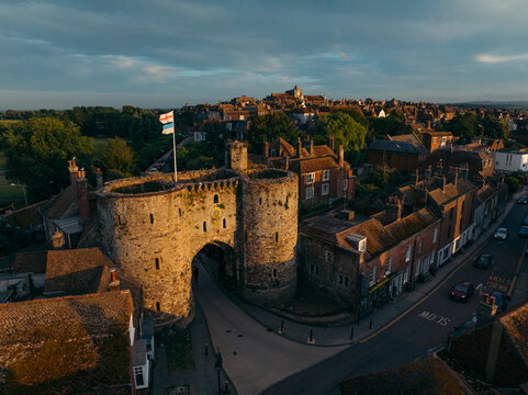 Aerial view of the Landgate archway bathed in golden sunlight with the town sprawling behind, Rye, England, United Kingdom.