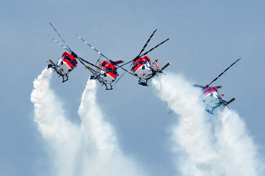 Aerial view of four helicopters on acrobatic display, in formation, with white smoke trails, a dance of precision and power, Changi Exhibition Centre, Singapore Air Show 2026, Singapore.