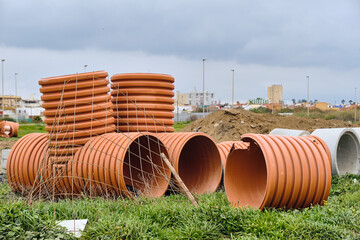 Obraz premium Infrastructure Development And Urban Planning Large Orange And Grey Concrete Pipes Stacked On Grass In La Linea De La Concepcion Andalucia Spain