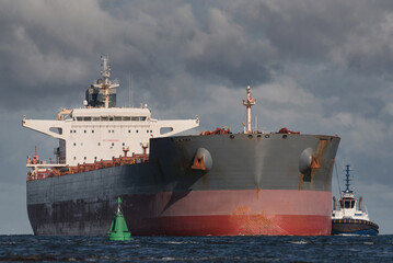 MARITIME TRANSPORT - Bulk carrier, and tug sailing at the sea to port