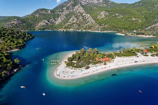 Aerial view of the vivid turquoise lagoon embraces the sandy shores of Oludeniz, crowned by verdant hills, a tranquil oasis of vibrant blues and greens, Oludeniz, Mugla, Turkey.