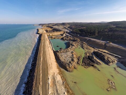 Aerial view of a stark contrast where the turquoise water meets the mined muddy shoreline, revealing environmental impact against the backdrop of the forest, Istanbul, Istanbul, Turkey.