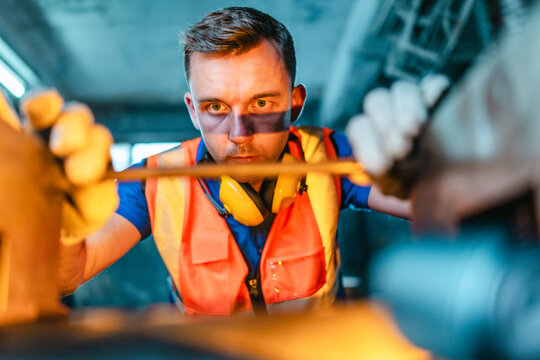 Technician Adjusting Heavy Industrial Machine in Traditional Metal Workshop
