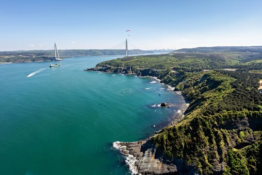 Aerial view of Yavuz Sultan Selim Bridge over the Bosphorus Strait, where turquoise waters meet rugged coastlines and lush green forests, Istanbul, Istanbul, Turkey.