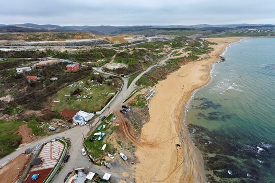 Aerial view of the contrasting textures of the sandy beach meeting the restless sea, alongside a road winding through the landscape, Istanbul, Istanbul, Turkey.