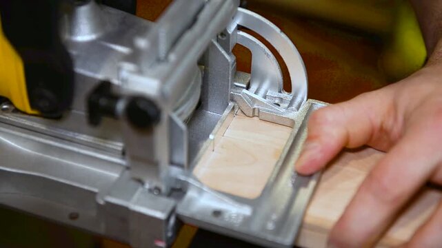 Wood lamella router in action cutting into a wooden surface. The spinning bit carves a precise groove as the attachment cutting into the material.