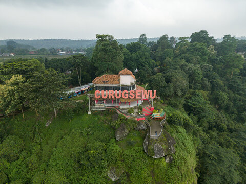 Aerial view of the Curugsewu landmark perched atop a verdant hill, a striking contrast against the dense foliage, Kendal Regency, Central Java, Indonesia.