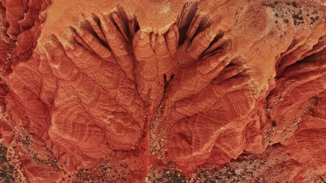 A view of a canyon showing unique rock formations. The color of the rocks is warm and reddish. The scene captures the details of the landscape under sunlight.
