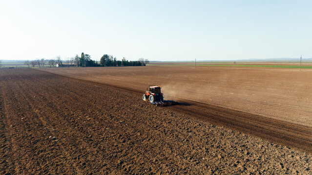 Aerial view of a lone tractor tilling the soil, creating a stark contrast between the dark earth and the lighter fields, Sremska Mitrovica, Vojvodina, Serbia.