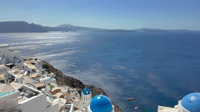 Oia, Santorini, Greece: Whitewashed buildings and blue-domed churches cling to the caldera cliffs overlooking the Aegean Sea, a popular tourist destination.