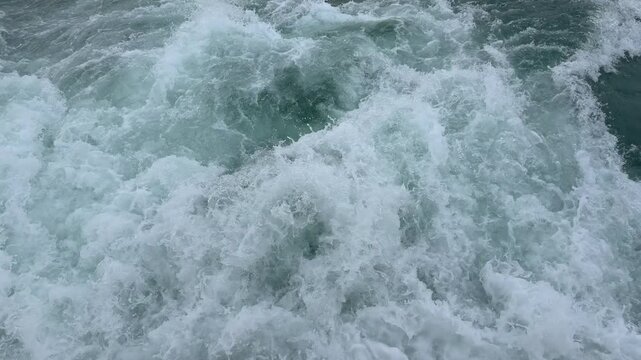 Mesmerizing slow motion top view of powerful ocean waves crashing and churning. Beautiful dynamic white sea foam and splashing water creating an abstract marine nature background.