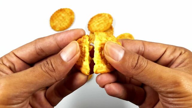 Hands expertly break a golden crispy round snack in half, revealing its delicious textured interior against a clean white background footage.