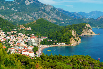 Fototapeta premium Aerial shot of the coastal town of Petrovac with its beach and green hills in Montenegro.
