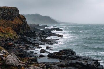 Obraz premium Rugged Northern Ireland coast with basalt cliffs and crashing surf under moody skies
