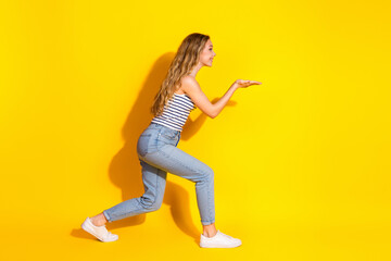 Smiling Young Woman in Casual Outfit Gesturing Excitedly Against Bright Yellow Studio Background...