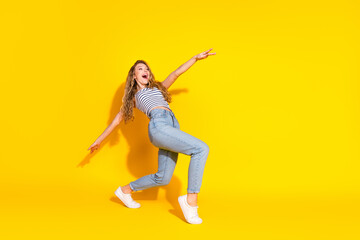 Young woman joyfully posing in a vibrant yellow background wearing casual fashion style with a...
