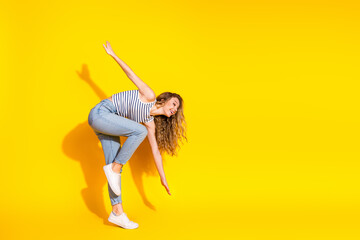 Joyful young woman with blonde hair posing on a vibrant yellow background showcasing her casual...
