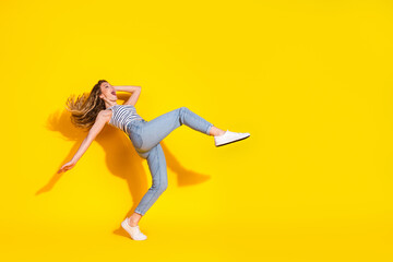 Energetic young woman jumping joyfully on a yellow background, portraying a sense of happiness,...