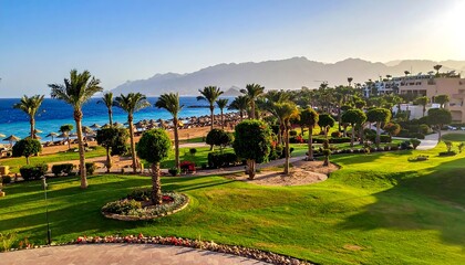 Obraz premium Scenic resort with palm trees, ocean view, and distant mountains under a blue sky