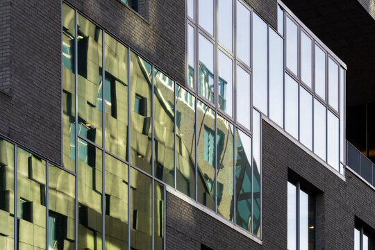 Brick and glass architecture facade with windows reflections and geometry pattern detail on a modern building creating a textured modern background
