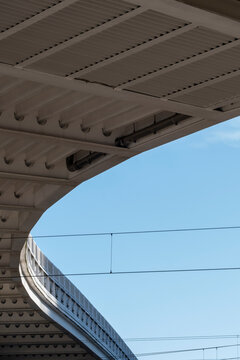 Modern architecture structure with steel beams and sweeping curves from the underside against sky showing geometry pattern detail as a clean background