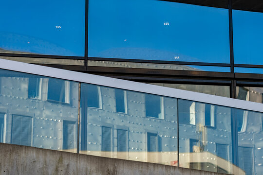 Blue glass windows architecture facade with reflections creating abstract geometry pattern on a modern building forming a clean modern background for design