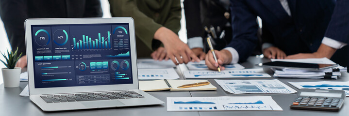 Fototapeta na wymiar Panorama shot analyst team utilizing BI Fintech to analyze financial report with laptop. Businesspeople analyzing BI data dashboard displayed on laptop screen for business insight. Prodigy