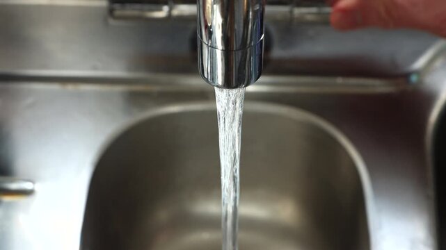 Close up of hand turning on and off mixer tap in Kitchen