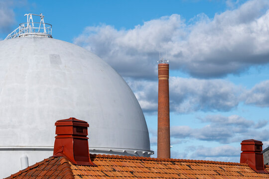 Industrial refinery landscape with dome storage tank chimneys and rooftop infrastructure under open sky