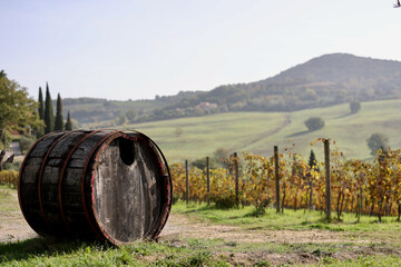 Obraz premium Sunny autumn day in Montepulciano, Province of Siena, Tuscany, Italy. A rustic wooden wine barrel stands beside vineyards with rolling hills.
