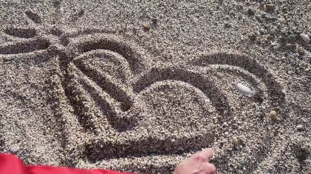 Beach heart drawing of a romantic symbol into the coarse sand on a pebble shoreline by a creative person