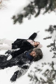 High angle of cheerful boyfriend and girlfriend having fun together in snowy winter forest 