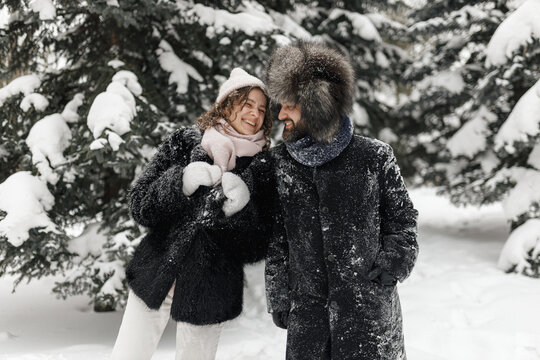 Delighted couple laughing and having fun in winter park while looking at each other  